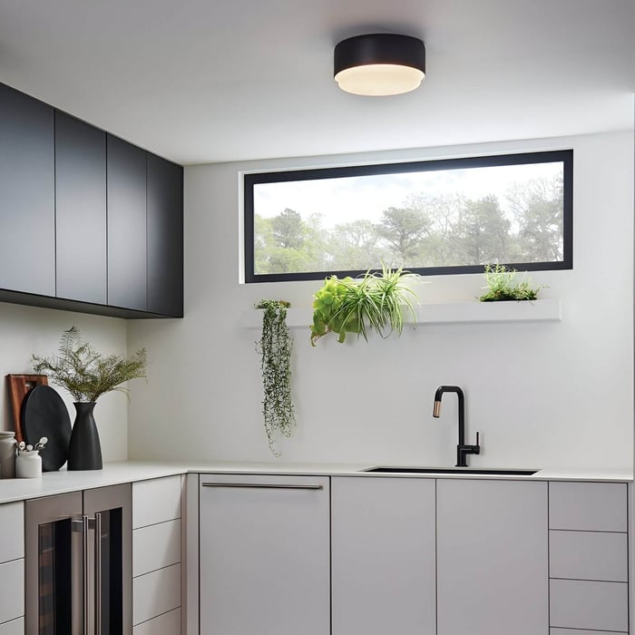 Minimal kitchen with sleek cabinets, plants, and round black flush mount ceiling light.