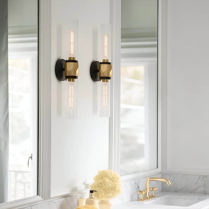 Pair of modern wall sconces mounted beside a bathroom mirror above a marble vanity with brass tap.