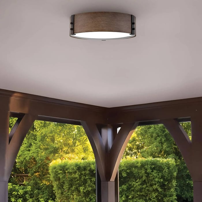 Close-up of a modern round flush ceiling light fitted under a gazebo roof.