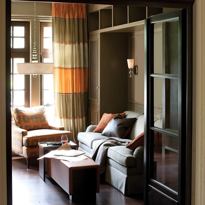 Warm-toned living room with drum pendant, orange accents & wood furnishings