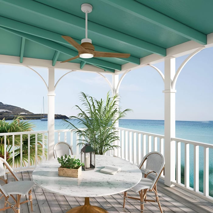 Wooden blade ceiling fan with light fixture on a turquoise patio overlooking the ocean.