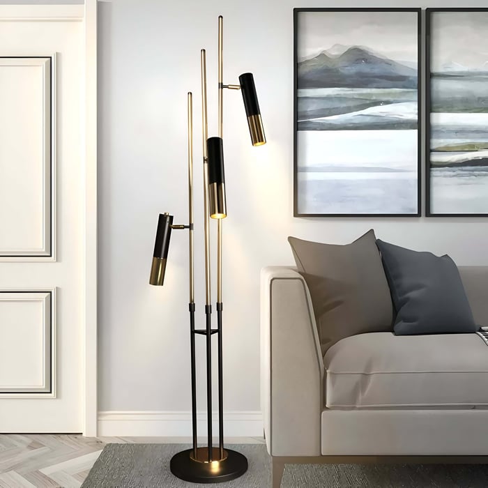 Modern black-and-gold multi-head floor lamp beside a neutral sofa in a contemporary living room with abstract landscape artwork on the wall.