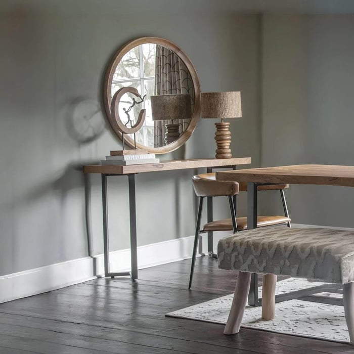 Turned-wood industrial table lamp with a woven drum shade on a hallway console beneath a round mirror.