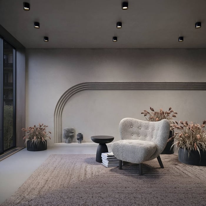 Stylish living room with black ceiling downlights creating soft ambient lighting over textured wall and armchair.