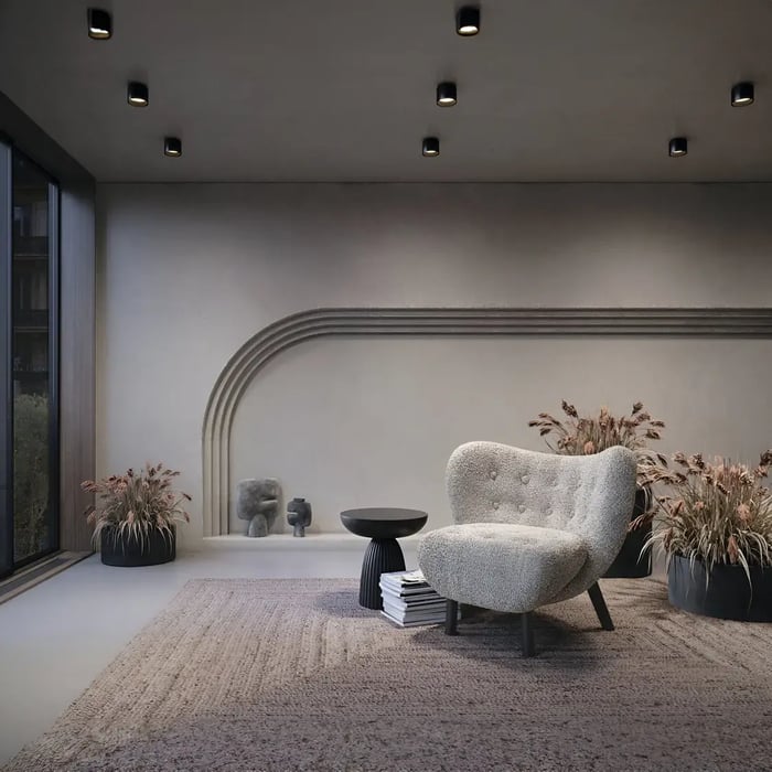 A modern lounge area with soft lighting from recessed fixtures in the ceiling, creating a relaxed and inviting ambiance with contemporary furniture and earthy tones.