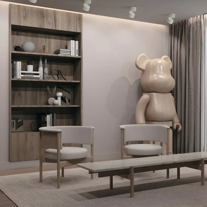  A cozy reading corner with a modern aesthetic. A wooden bookshelf displays books and decor items, accompanied by neutral-toned chairs and a playful oversized bear sculpture, all softly illuminated by white ceiling spotlights.