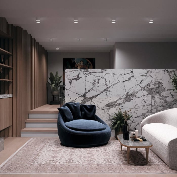 Modern lounge interior with evenly spaced recessed downlights above marble feature wall and seating area.