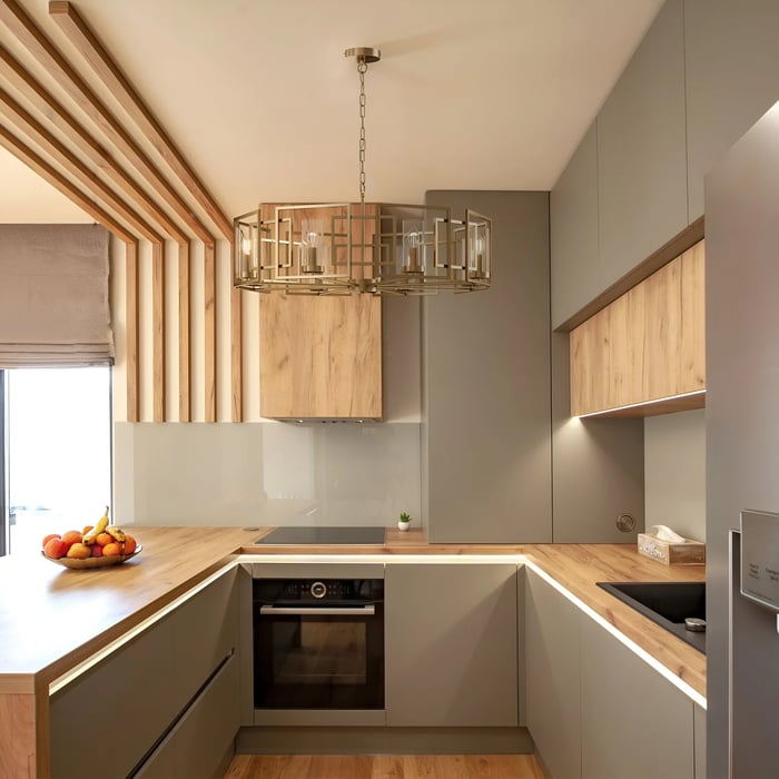 Small contemporary kitchen lighting with light wood and grey cabinets, featuring a large, ornate metal pendant light hanging in the centre.