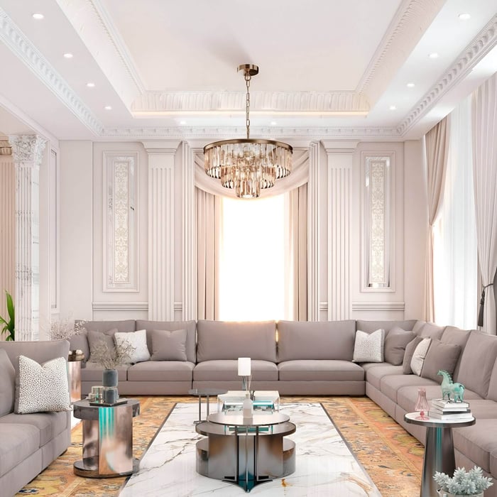 Round crystal chandelier centered over a grey sectional in a bright, classically styled living room.