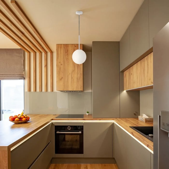 Scandinavian-style kitchen with wood and olive cabinets, accented by a round pendant and soft under-cabinet kitchen lights.