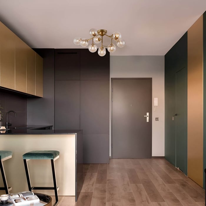 Brass mid-century chandelier with exposed globe bulbs in a sleek kitchen space.