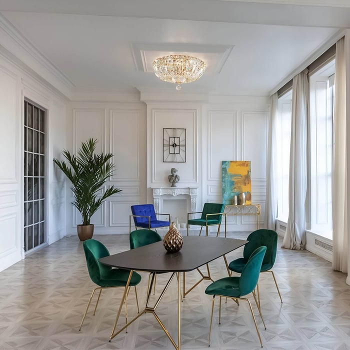 Low-profile crystal flush-mount chandelier in a white-paneled room with jewel-toned velvet dining chairs.