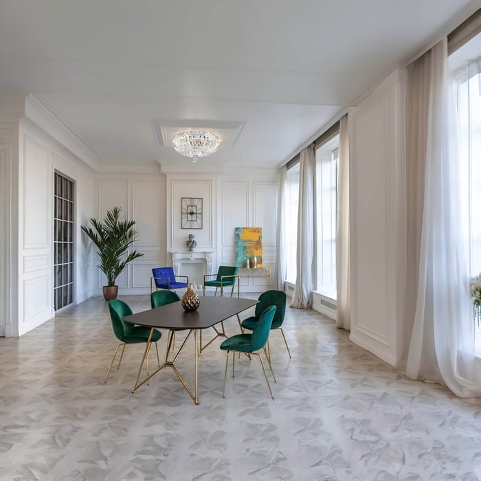 Spacious dining room with green velvet chairs and crystal ceiling light in a white interior.