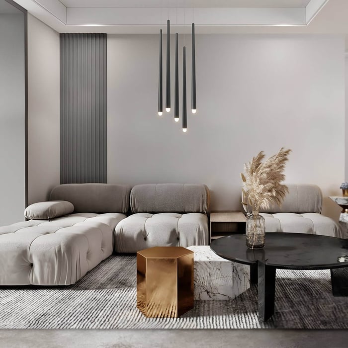 Neutral-toned living room with tufted seating, modern pendant lighting, and mixed-material tables.
