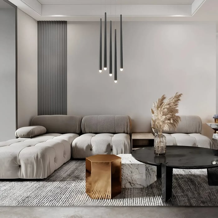 Modern living room with neutral tones, featuring a cluster of long, cylindrical pendant lights hanging above a plush sectional sofa and a sleek, metallic coffee table.