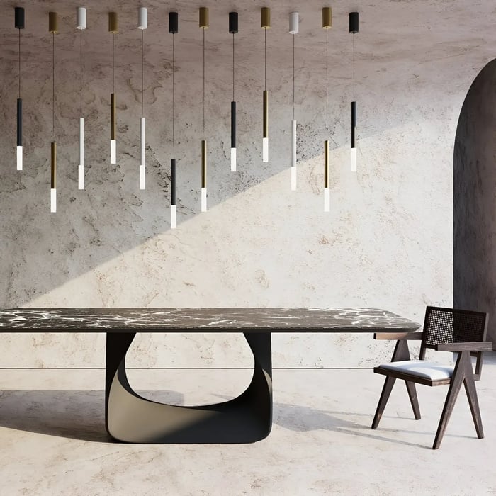 Contemporary space with a sleek black table and a statement pendant light installation consisting of thin, tubular hanging lights in varying heights, set against a textured wall.