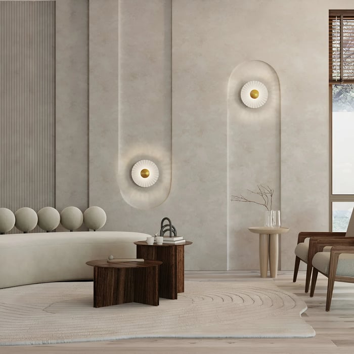Elegant living room with beige tones, highlighted by sculptural wall-mounted lights emitting a soft glow. The space features a curved sofa, wooden side tables, and textured walls.