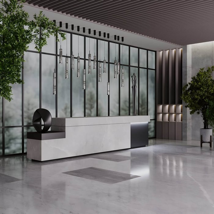 Modern lobby with marble reception desk, tall pendant lighting, and glass wall backdrop.