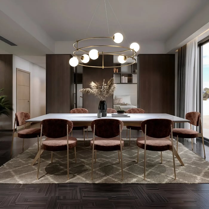 Elegant dining space featuring a long rectangular dining table with plush, velvet-upholstered chairs. Above the table, a circular chandelier with multiple globe-shaped lights hangs, adding a modern touch to the room.