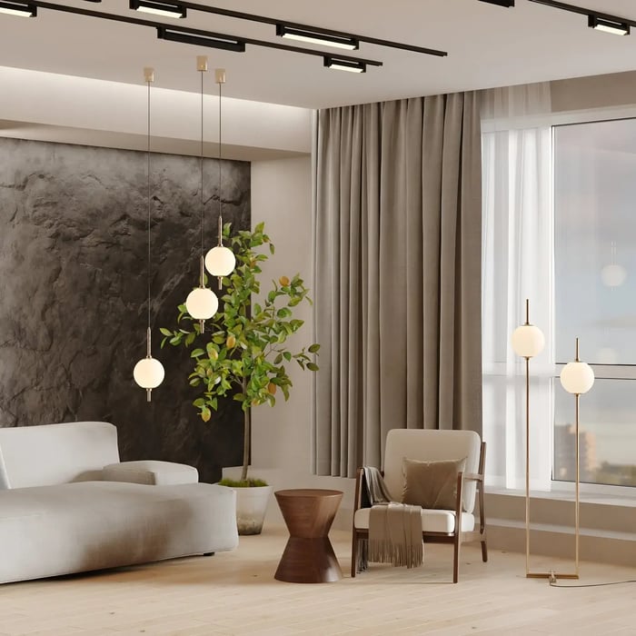A stylish living area featuring pendant lights, a modern lounge chair, a small wooden side table, and a pair of spherical floor lamps in front of floor-length curtains.
