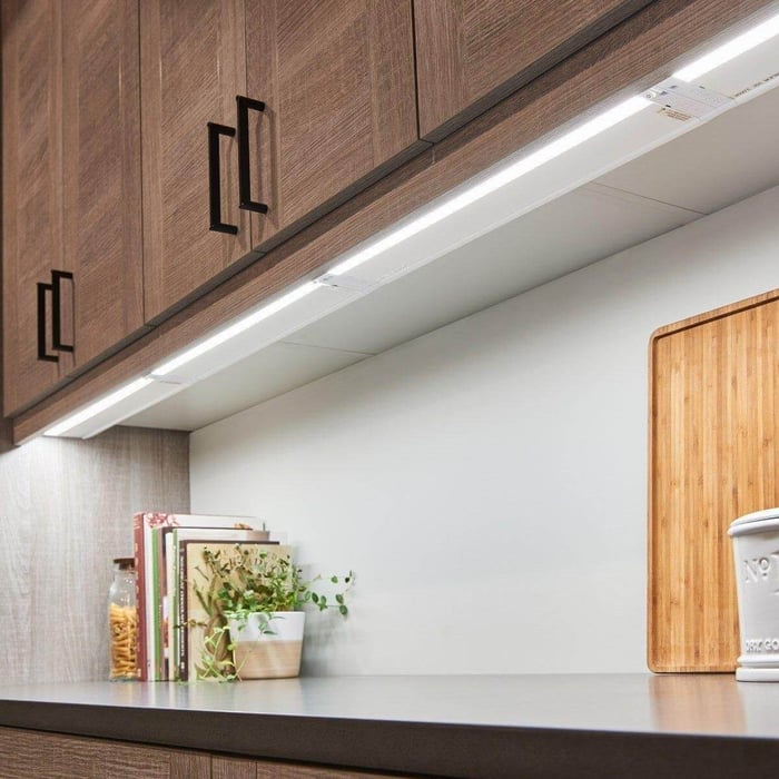 LED strip lighting fitted beneath wooden wall cabinets to light the kitchen work surface.