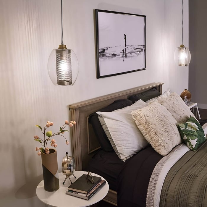 Bedroom with twin pendant lights, layered pillows & black-and-white artwork