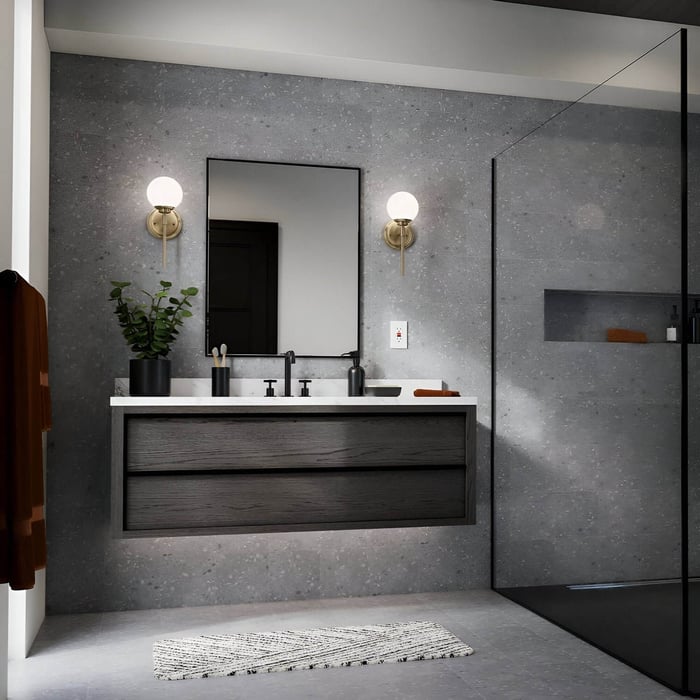 Minimalist bathroom with gray stone walls, black floating vanity, rectangular mirror, and globe wall sconces with brass bases.