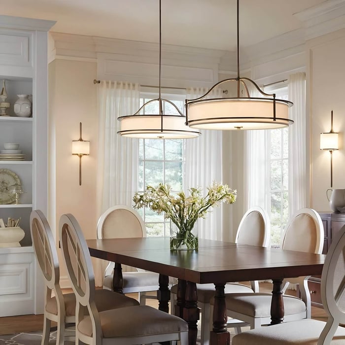 Classic dining room with matching round pendant lights, soft neutral chairs, and wall sconces.