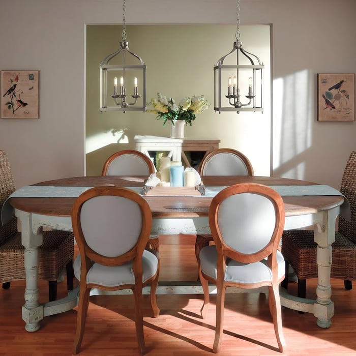 A dining room with two hanging lantern-style lights over a rustic wooden table, surrounded by upholstered chairs with curved wooden frames.