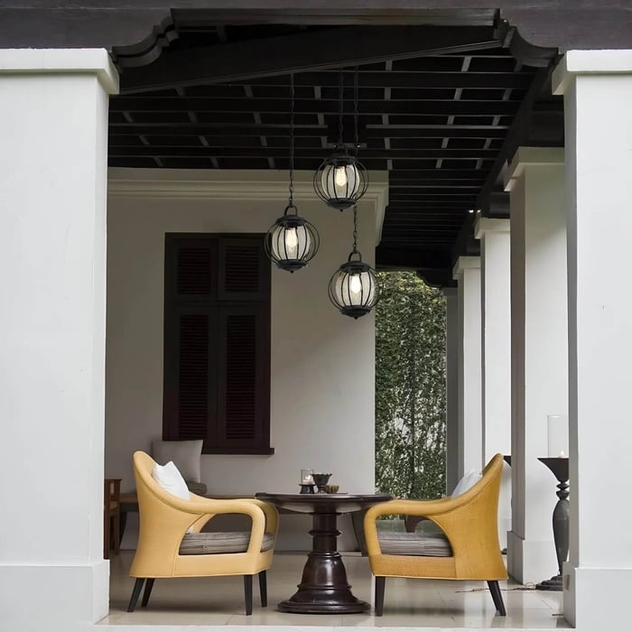 Veranda seating nook with three globe-style hanging pendant lights over a small table.
