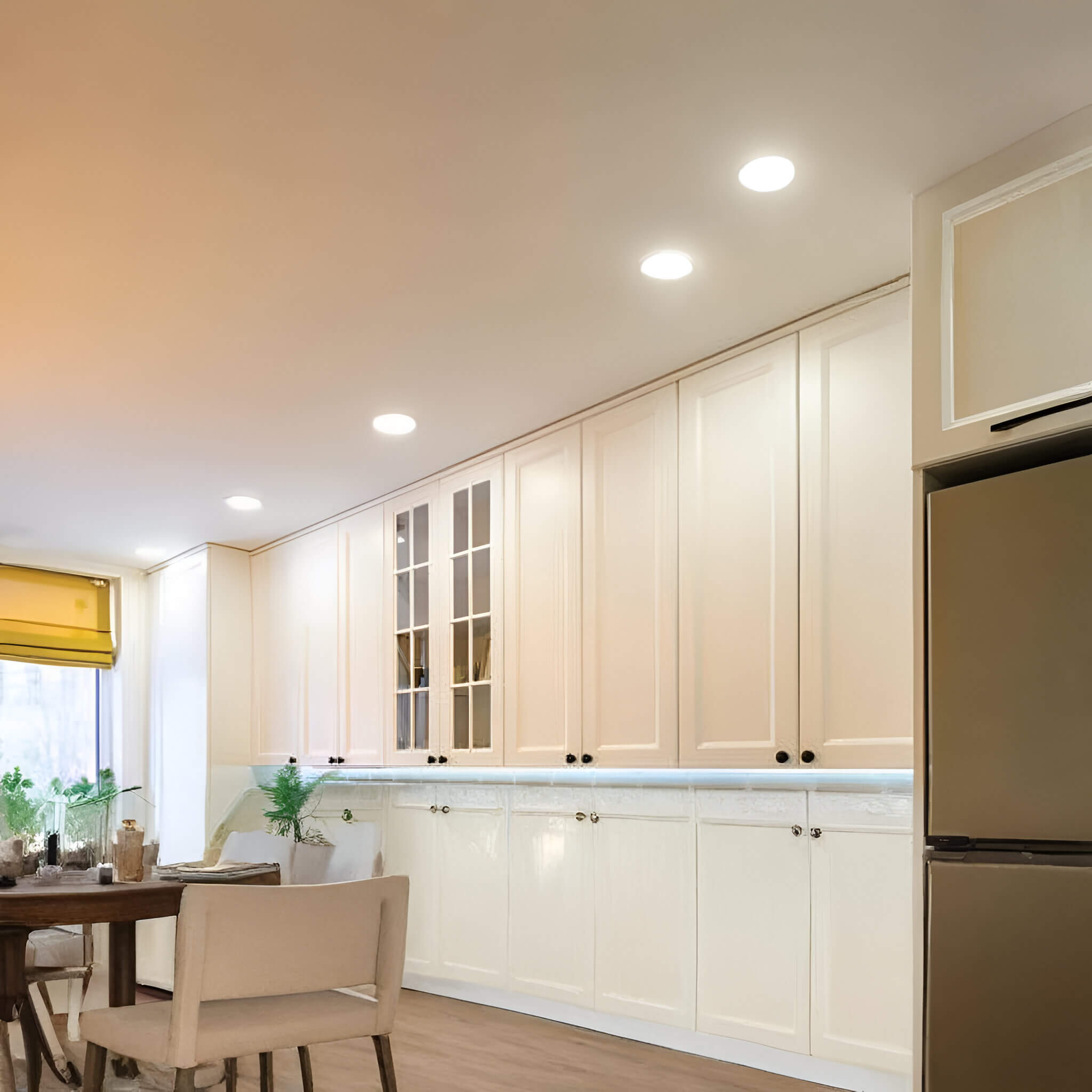 Bright white kitchen with multiple recessed ceiling LED lights and under-cabinet strip lighting.