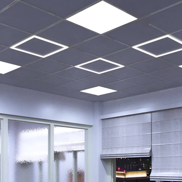 Office ceiling grid with multiple square LED panel lights evenly lighting a meeting room.
