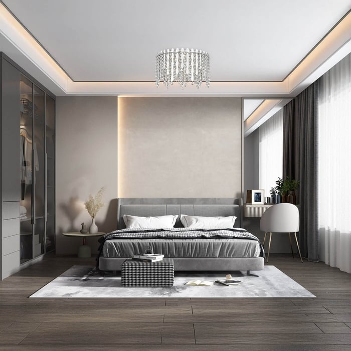Bedroom with a crystal chandelier centered on the ceiling, soft neutral decor, and natural light from a large window.
