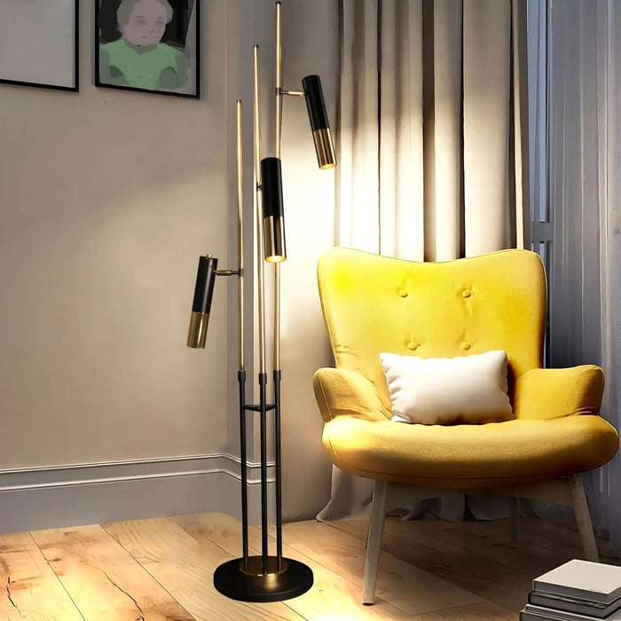 Multi-head black and gold floor lamp casting warm light beside a mustard yellow armchair.