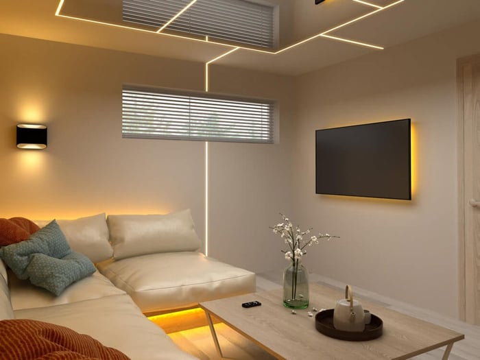 Modern living room with recessed LED strip lighting on the ceiling, vertical wall line, and warm under-sofa glow near a wall-mounted TV.
