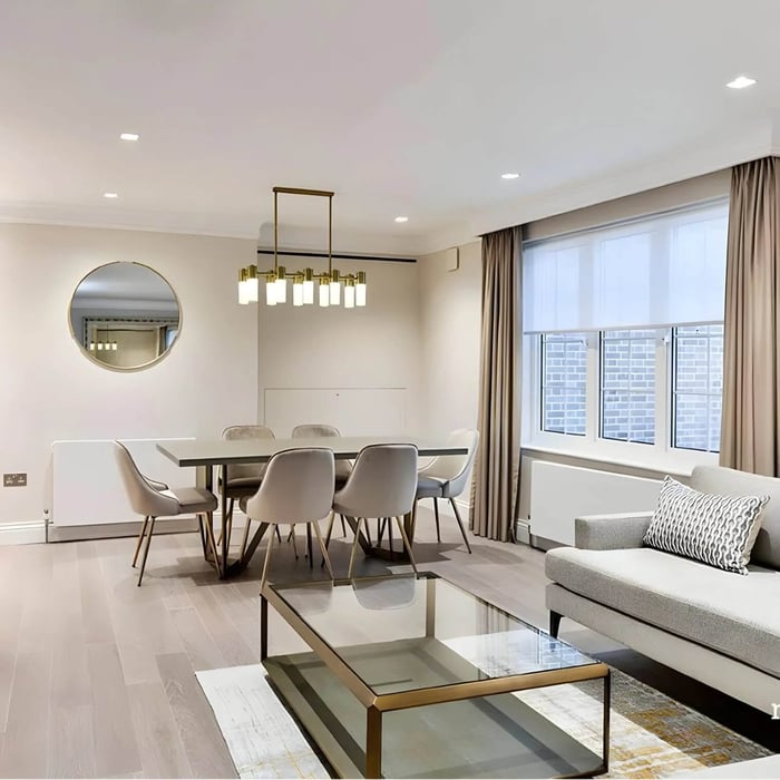 Rectangular gold linear pendant with glass shades hung above a dining table in a bright open-plan living and dining area.