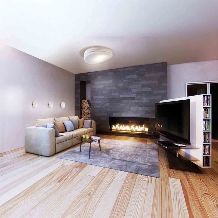Simple round flush mount ceiling light in an open modern living room with wood floors.