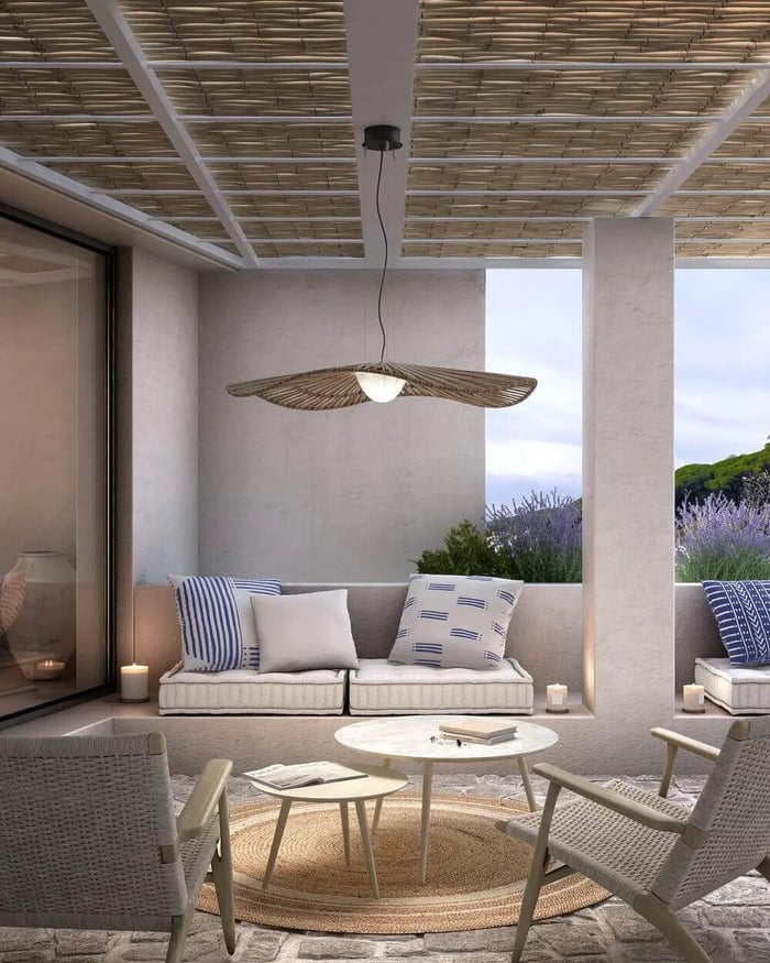 Covered terrace lounge with a wide natural-fibre pendant light centred above a seating area.