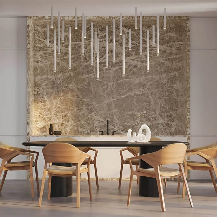 Contemporary linear white pendant dining room lights above wooden dining table with marble backdrop.