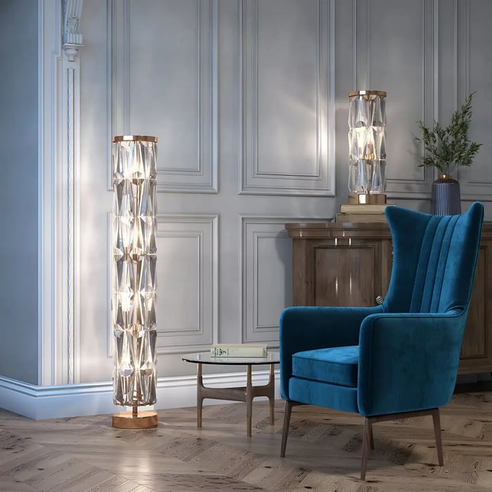 Two crystal-styled modern floor lamps emitting warm light in an elegant room with a blue velvet chair, a small glass-top side table, and panelled walls for a sophisticated touch.