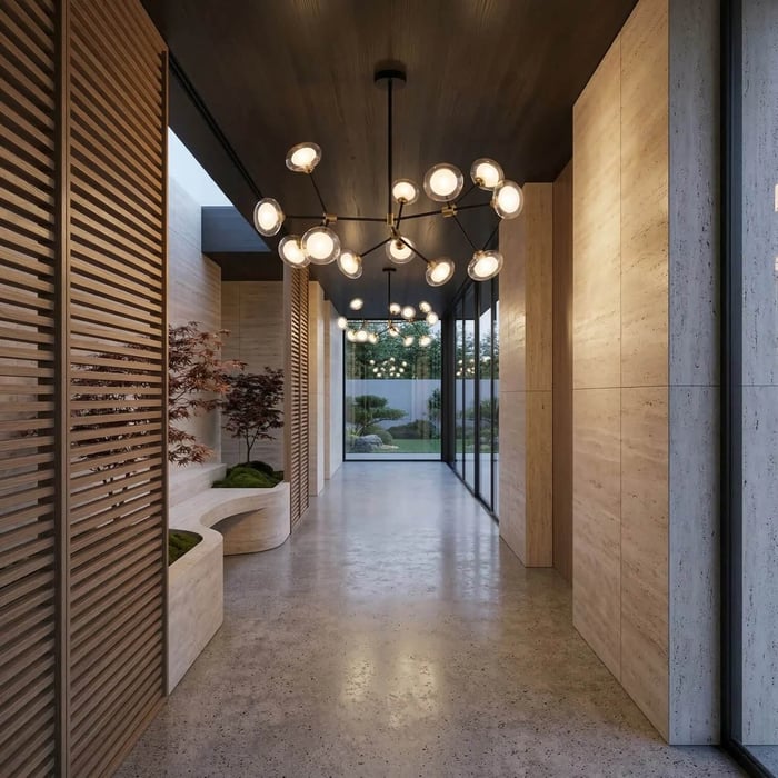A long, moody hallway with dark wood ceilings and polished concrete floors. Multiple black branching chandeliers with round glass bulbs lead the eye toward a glass wall at the end, bordered by slatted wooden screens and indoor greenery.
