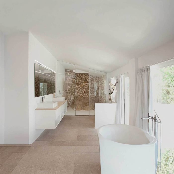 Bright modern bathroom with freestanding tub, floating double vanity, and glass shower with stone feature wall.