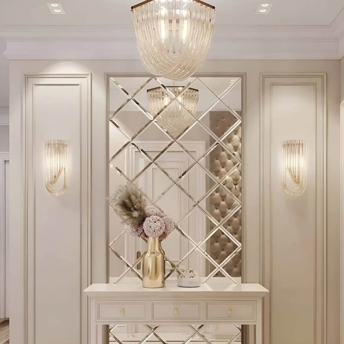 Gold crystal chandelier suspended above a dining table in a refined interior with marble surfaces and framed wall artwork.