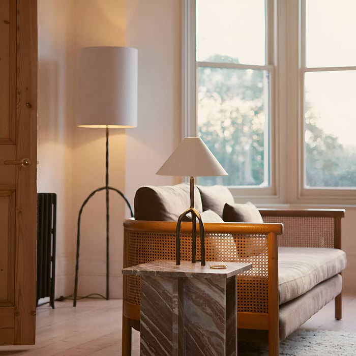 Bright sitting area with rattan sofa, marble side table, and two warm-toned lamps.