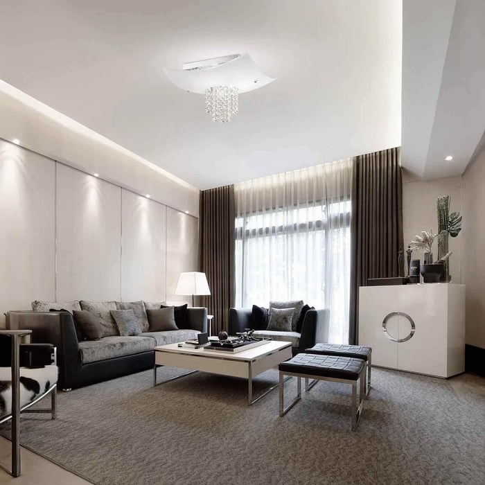 Modern living room with a white flush ceiling light and hanging crystal detail above the seating area.