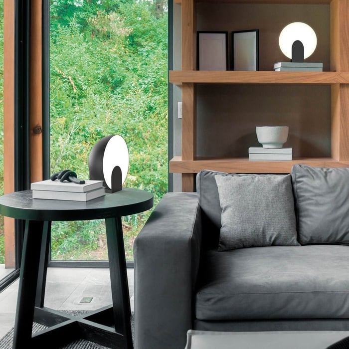Contemporary living room with circular black and white table lamps and wooden shelving.