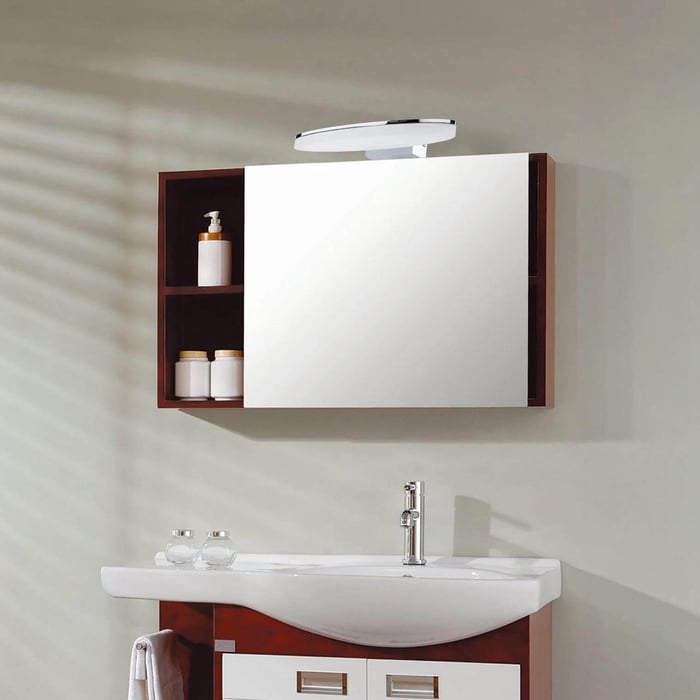 Wall-mounted mirrored cabinet with LED light above, positioned over a modern sink and tap.