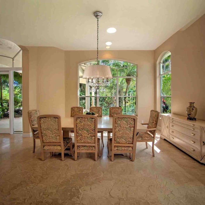 Drum shade chandelier with hanging crystal drops above a dining table in a beige room with arched windows.