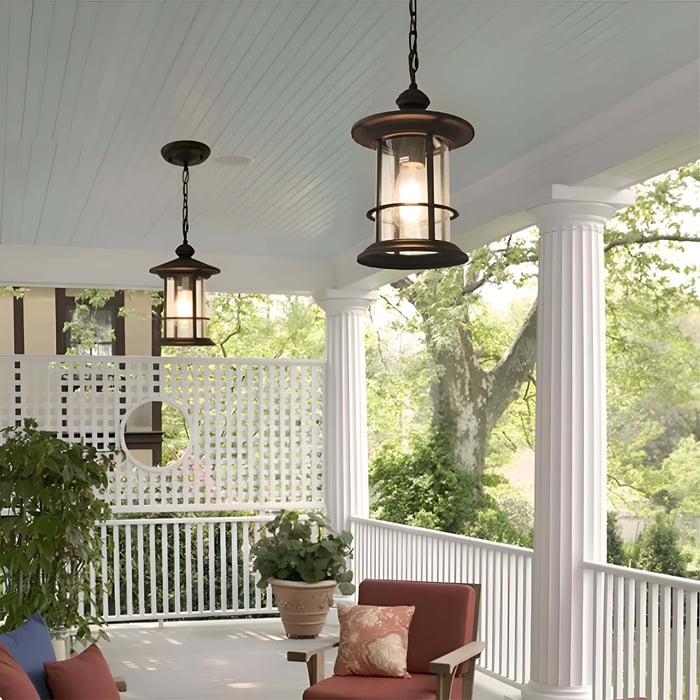 Bronze lantern-style pendant lights hang from a light blue porch ceiling with white columns, lattice privacy screen, red cushioned chair, potted plants, and leafy trees beyond.