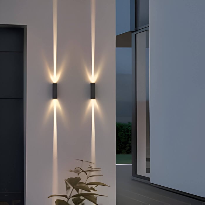 Pair of vertical up-and-down outdoor wall lights creating narrow light beams on a white façade near large windows at dusk.